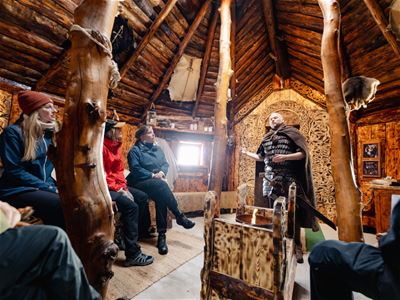 Guests listening to stories about Viking life and culture inside one of the buildings at the Viking village.