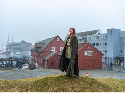 Guiden står på en haug ved siden av Polarmuseet i frakk
