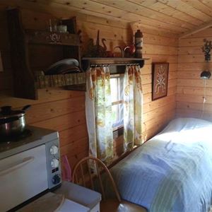 En säng och en bänkspis med två kokplattor samt ugn.