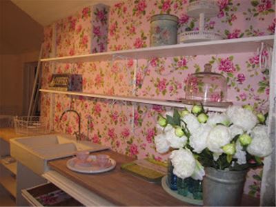 Interior image from the café, floral wallpaper, white shelves.