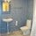 Wc och handfat i badrum med blått kakel och naturfärgat klinkers. 