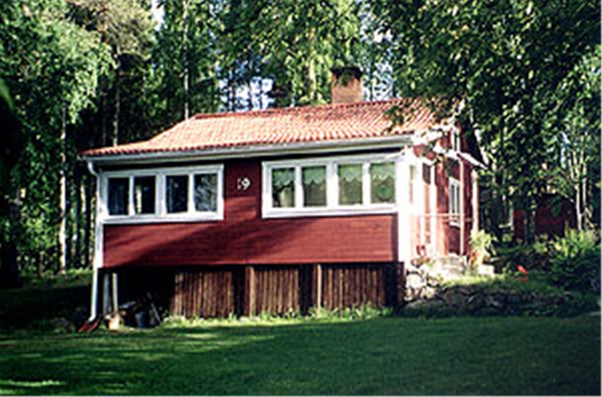 Röd stuga med inbyggd veranda.