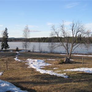 Utsikt från stugan över sjön med gräsmatta framför.