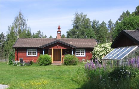 Red log cabin with flowers in the garden.