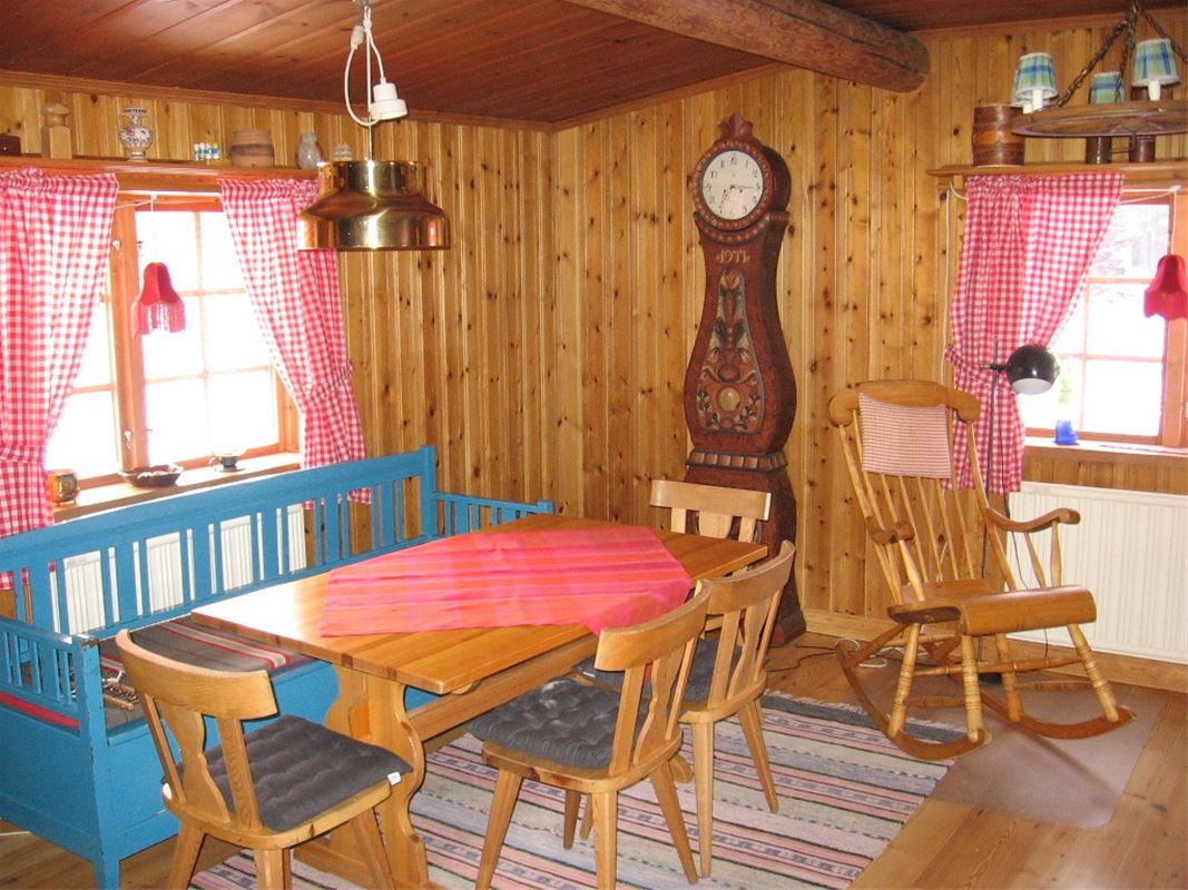 Matplats med kökssoffa och fyra stolar, intill finns en gungstol.