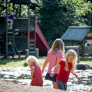 Children playing by water, in the background a playground.