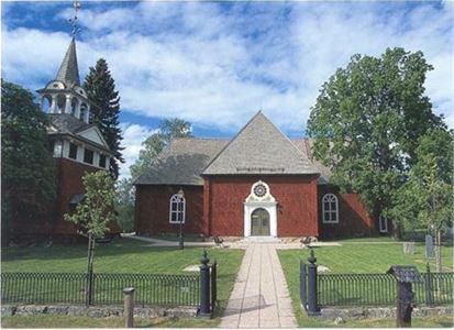 Sundborns kyrka, exteriörbild, röd träkyrka med grön dörr, svart järn staket, gång fram till kyrkan, klockstapel till vänster