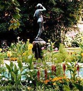 En staty föreställande en kvinna bland växtligheten i parken.