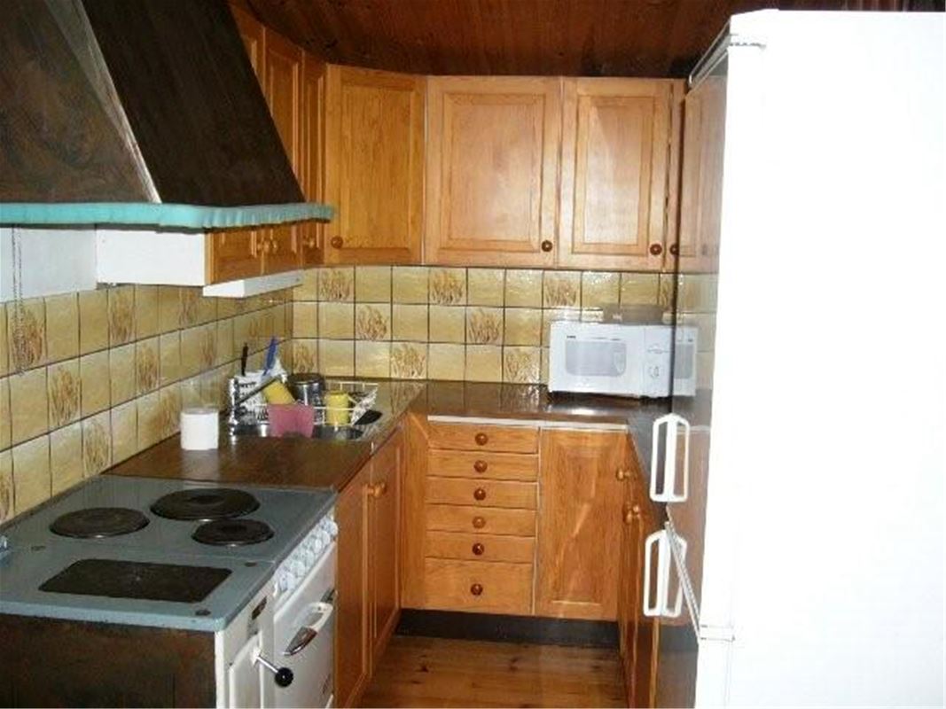 Kitchen with woodden cabinet doors and beige tiled walls.