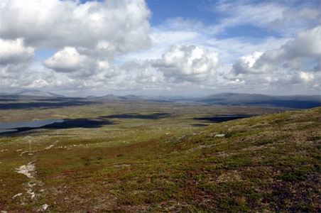 Vy från toppen, vatten ochbånande berg i bakrunden.