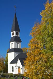 Särna church with autumn coloured trees and a blue sky