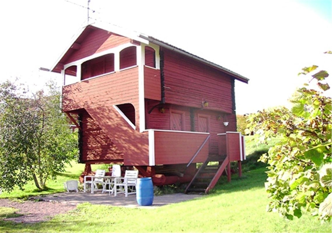 Red timber cottage in two floors with an outdoor stair to the upper floor. 