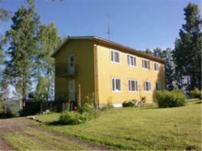 Big yellow house surrounded by trees.