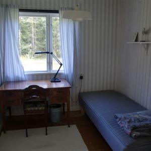 Sovrum med enkelsäng och ett skrivbord framför fönstret.