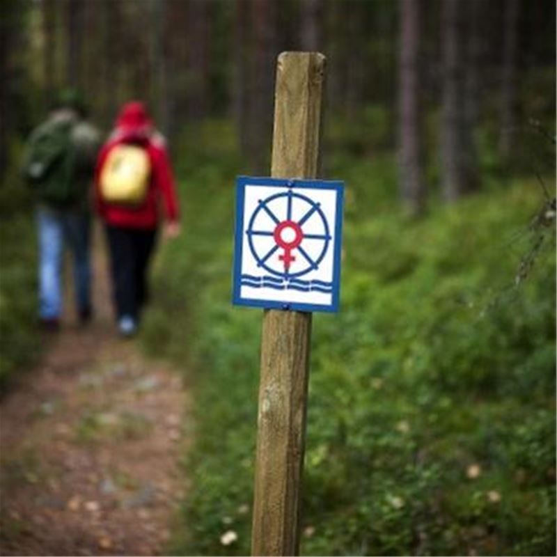 Trail marking on a stick, two hikers on the trail.