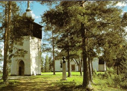 Barrträd framför det vita kapellet.