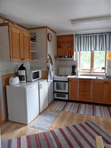 The kitchen with an electric stove, microwave oven and a coffee machine.