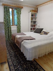 Bedroom with a double bed and a bookshelf next to the bed.