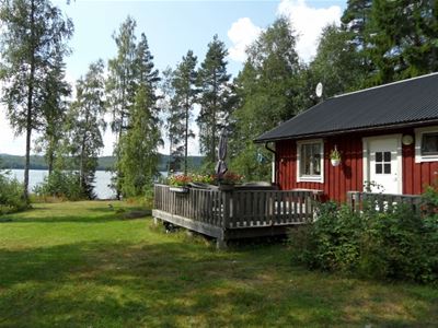 Red painter cottage with a large porch and the lake in the background.