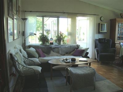 Vardagsrummet med soffa, två fåtöljer och pallar.