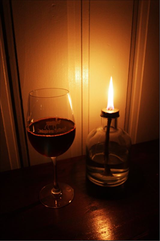 Ett rödvinsglas med tänt ljus bredvid
