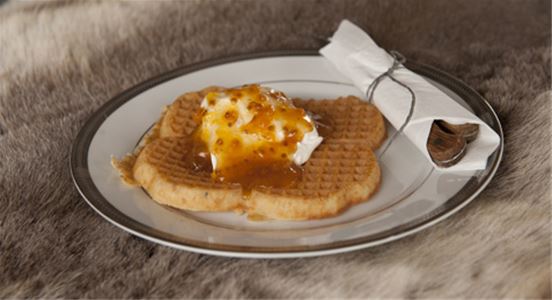 A waffle on a plate with cream and jam