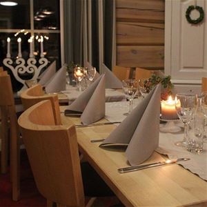 A set table with cutlery and napkins, lit candles on the table.