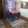 Matbord med två stolar framför ett fönster med lila, mönstrad gardin med matchande vaxduk. 