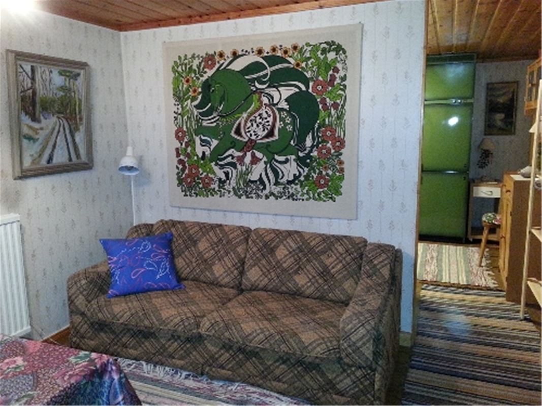 Brun-rutig soffa med en färgglad, grön väggbonad ovanför.