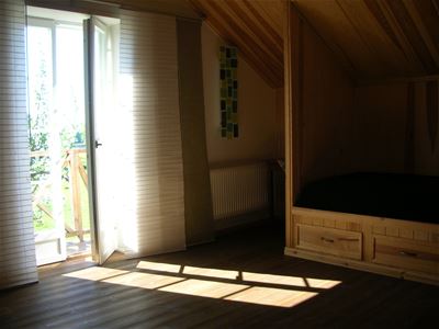 Sovrum med platsbyggd säng och en balkongdörr på glänt.