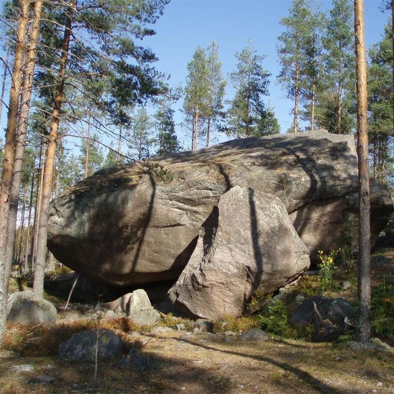 Large stone with surrounding pines.