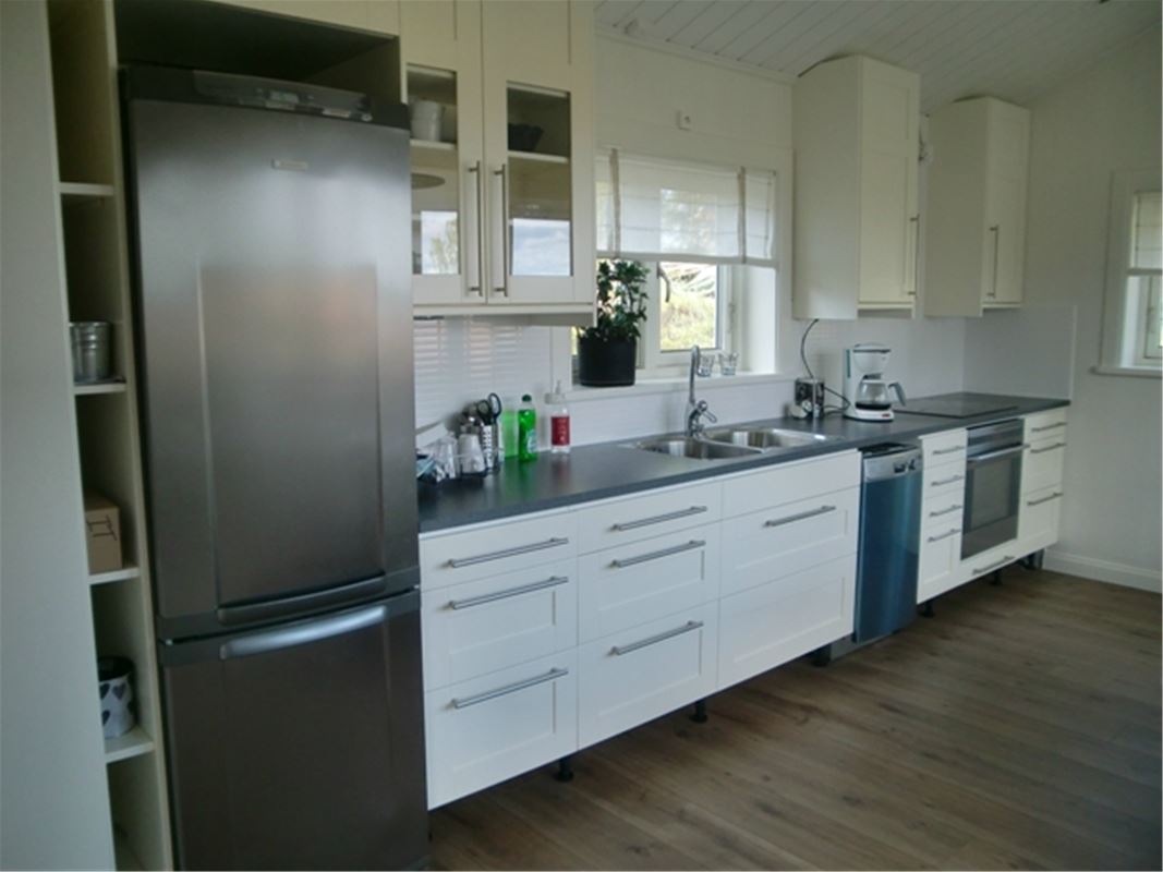 White kitchen with stainless steel fridge and freezer and a window over the sink. 