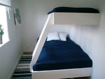 White bunkbed with a wider bed below. 