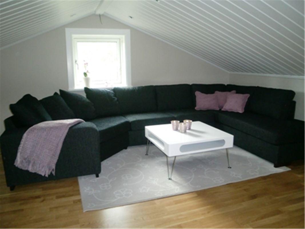Large black sofa in a bright room with sloping roof.