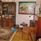 Vardagsrum med brun bokhylla, piano och en mönstrad matta på golvet. 