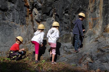 Fyra barn med hjälm nere i gruvan.