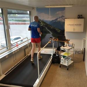 Man i blå tröja och röda shorts springer på ett löpband.