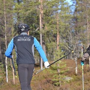Man i cykelhjälm blåa och svarta kläder håller stavar i händerna.