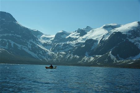 Gjest i en kajakk ser på snødekte fjell