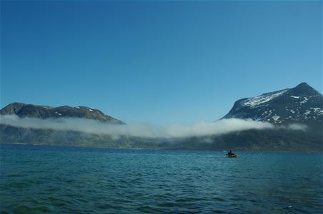 Kajakk ute på havet som ser inn mot tåkedekte fjell