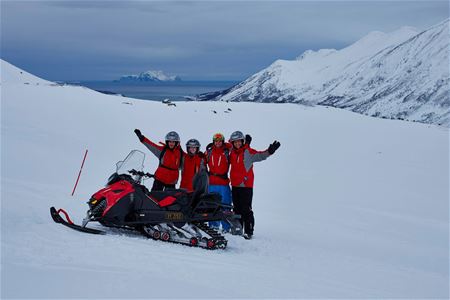 Guests posing behind snowmobile
