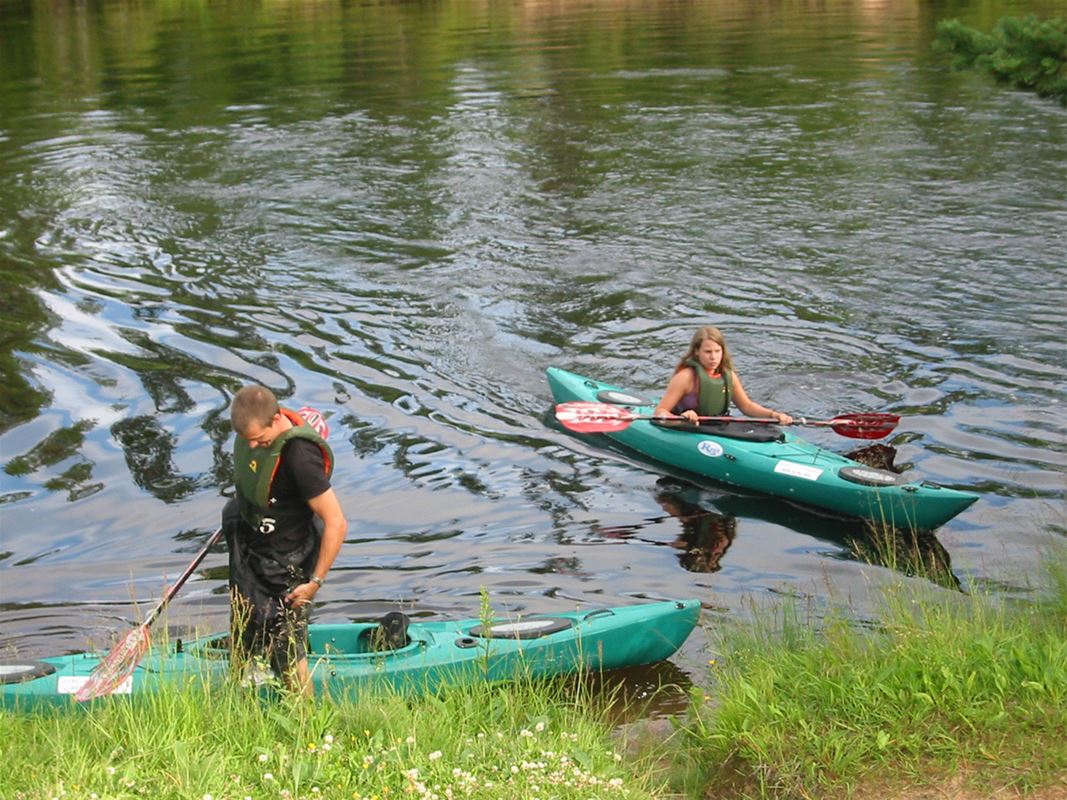 Two people in canoes on the river. 