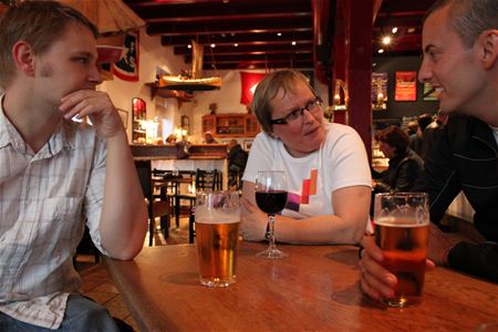Tre personer ved et bord med øl og vin i en maritimt dekorert bar.