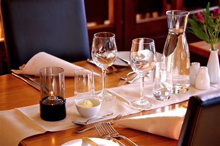 Set table in te restaurant with white napkins, glasses of wine and a carafe of water.