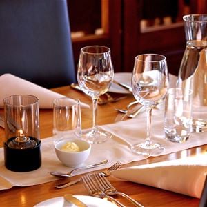 Dukat bord i restaurangen med vita servetter, vinglas och en karaff vatten. 