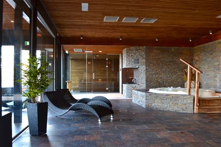 Två relaxstolar som står vid stora fönster och en bubbelpool.