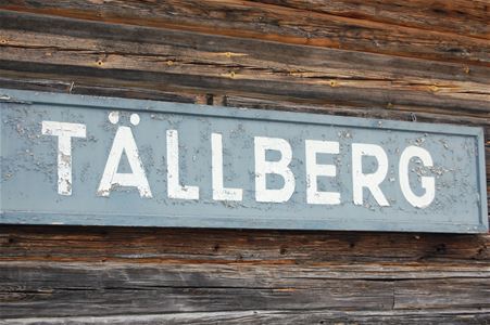 Sign of Tällberg placed on a brown timber wall. 