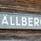 Skylt med namnet Tällberg sitter på en brun timmervägg. 