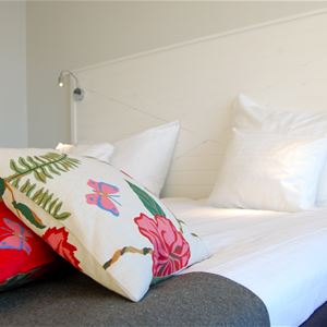 White and red, floral pillows on a bed.