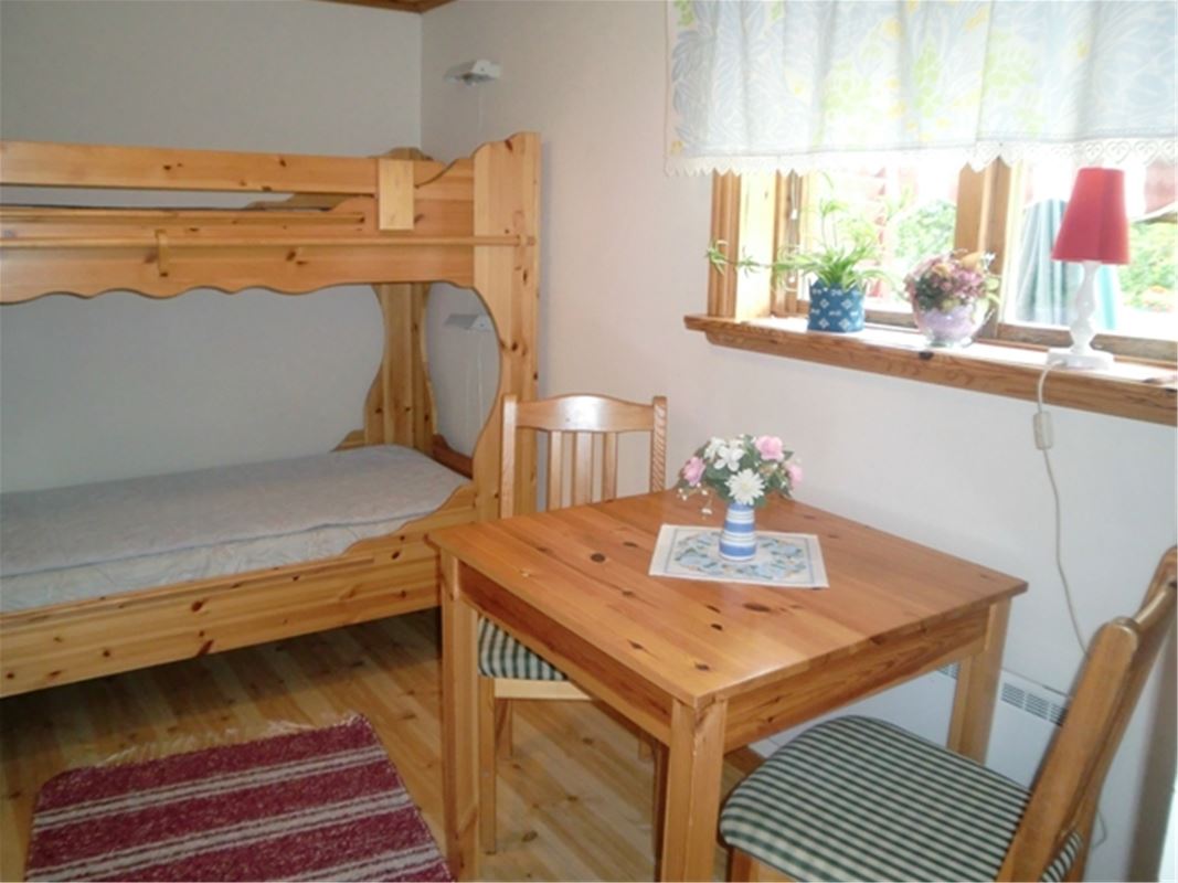 Bunkbed in pine and a table with two chairs by the window. 